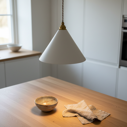 White pendant lamp hanging over a wooden table with a bowl and cloth in a kitchen.