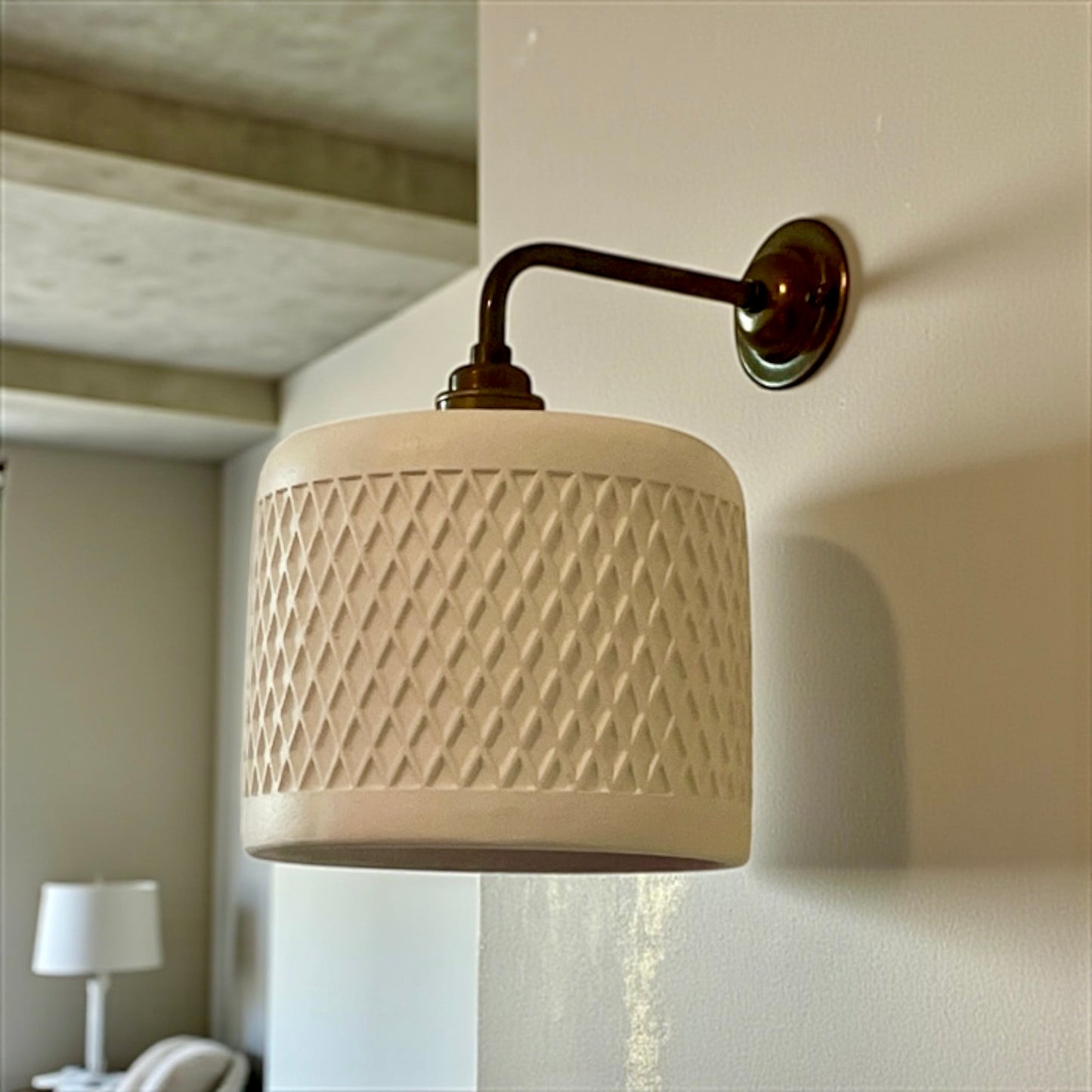 Handmade wall-mounted lamp with textured design on a white wall.