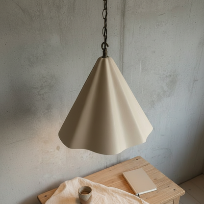 Beige pendant light hanging against a textured wall with a wooden table and cup in the foreground.