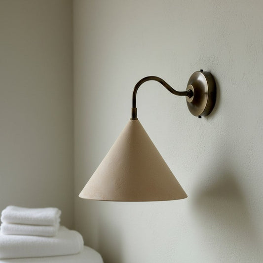 Beige wall lamp with a cone-shaped shade on a neutral wall.