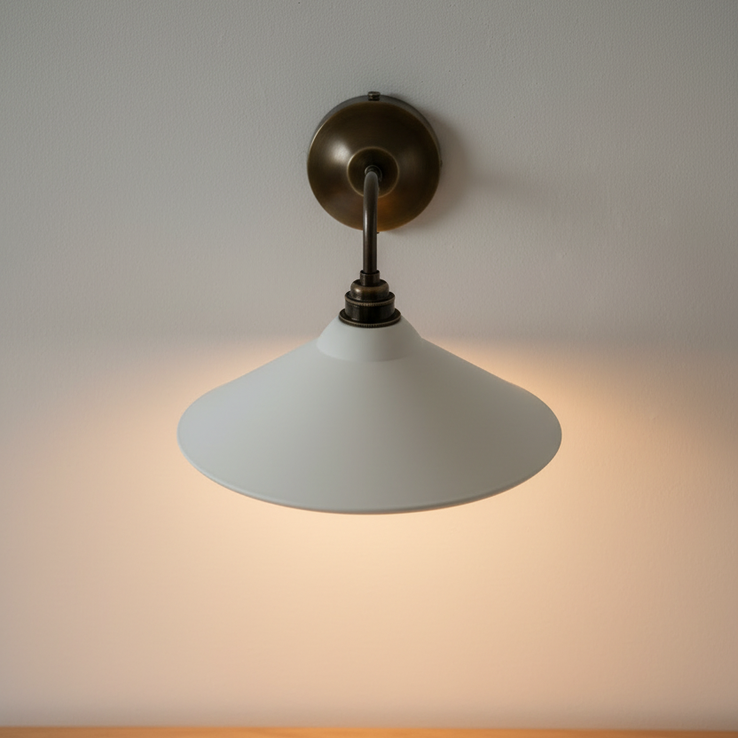 Wall-mounted light fixture with a white shade and bronze fixture on a neutral background