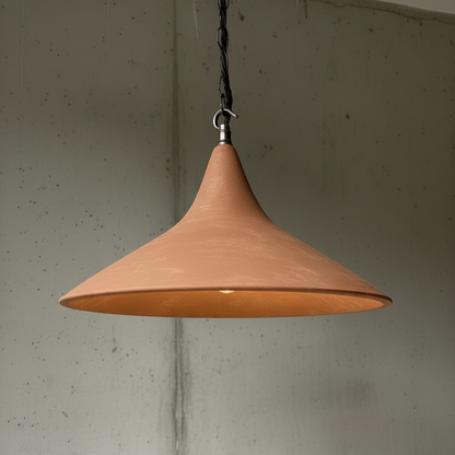 Pendant light with a terracotta-colored shade hanging against a textured wall.