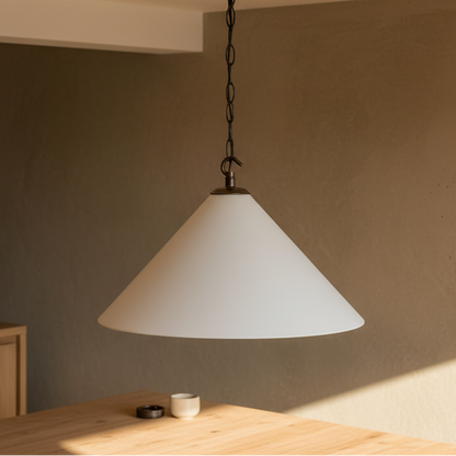 White pendant light hanging above a wooden table in a room with neutral walls.