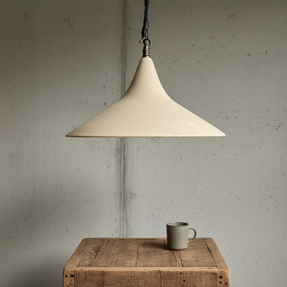 Sandstone pendant lamp hanging above a wooden table with a ceramic mug on a textured wall background