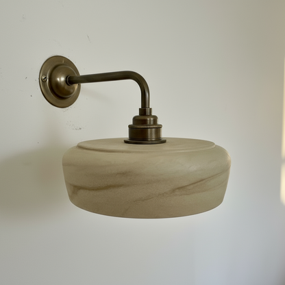 Wall-mounted light fixture with wooden shade and brass fitting on a white wall.