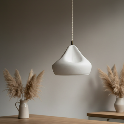 White pendant lamp hanging above a wooden table with decorative plants.