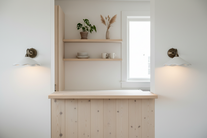 Light wooden kitchen island with shelves and wall lights in a bright room.