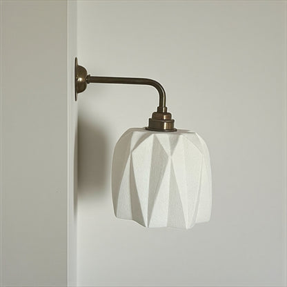 handmade wall sconce with geometric white shade and bronze arm on a neutral background