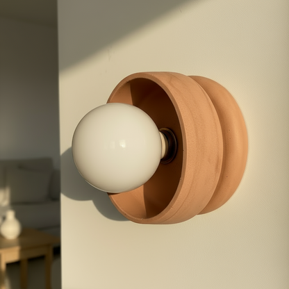 Terracotta wall sconce with a white bulb on a neutral background