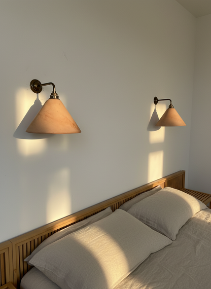 Bedroom with wooden headboard and wall-mounted lamps casting shadows on the wall.