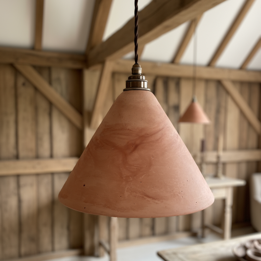 Terracotta pendant light hanging in a rustic wooden room with a table and chairs.