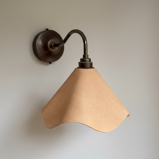 Wall-mounted lamp with a beige sandstone shade on a plain background