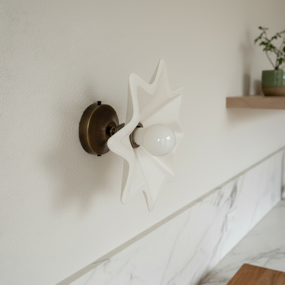 Decorative wall light fixture in a kitchen with marble countertop and wooden shelf.