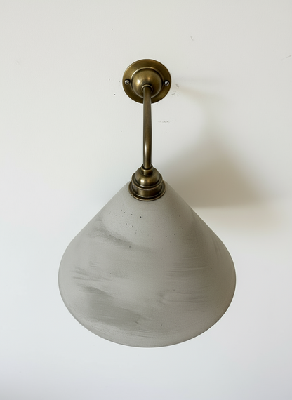 Wall-mounted light fixture with a concrete shade on a white background