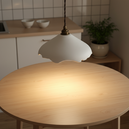 Round wooden table with a white sculptural pendant lamp in a kitchen setting