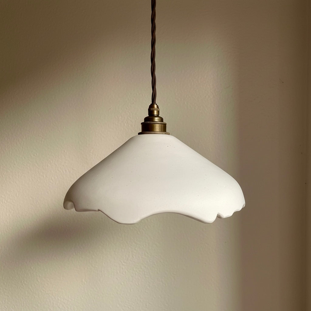 White pendant light with a scalloped edge against a beige wall