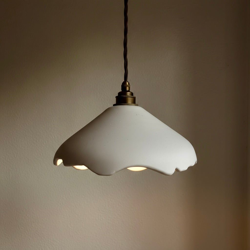 White hand-carved pendant light with scalloped edge on a neutral background